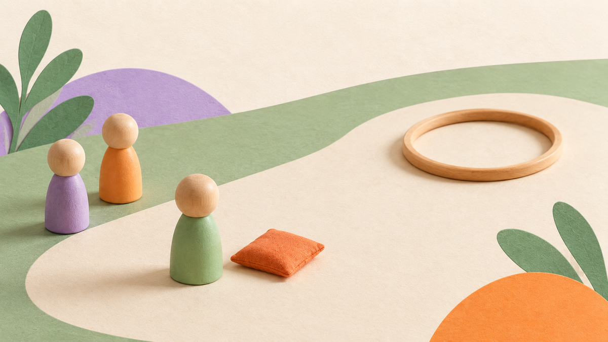 Three wooden peg figures are beside an open playing space, with a beanbag at the throwing position and a wooden hoop ahead.